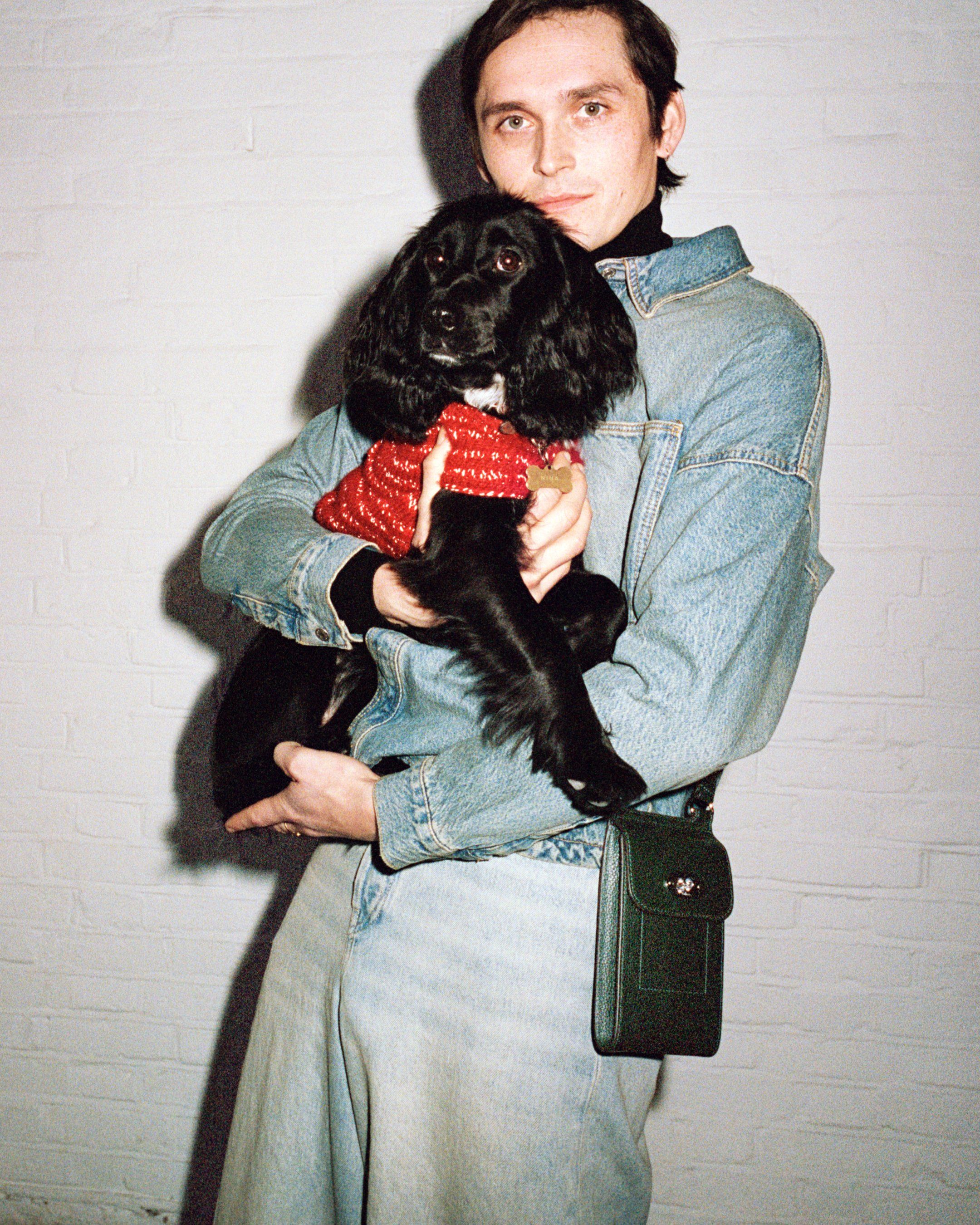 Model holding a dog and wearing the Mulberry Mini Antony bag in green leather